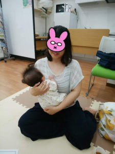 座って赤ちゃんを抱っこするお母さん